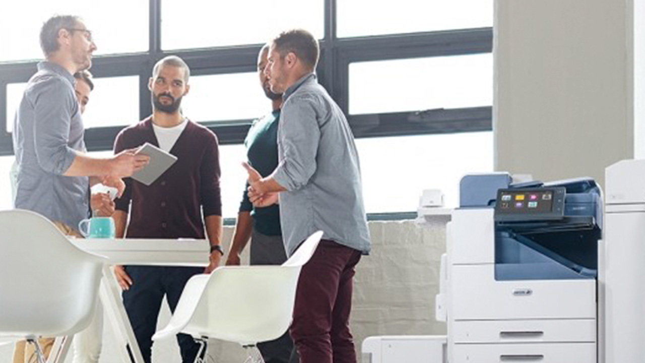 Constabilidad, seguridad, control costes Reunión de un equipo de trabajadores y al lado una máquina de impresión